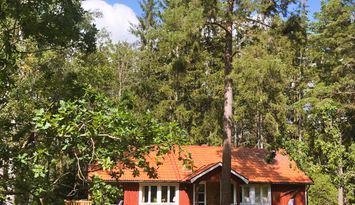 Hus mitt i skogen vid havsviken Syrsan