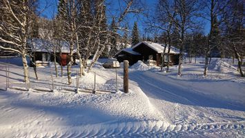 Skarvrustuga med längdspår och skidbuss som granne