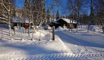 Skarvrustuga med längdspår och skidbuss som granne