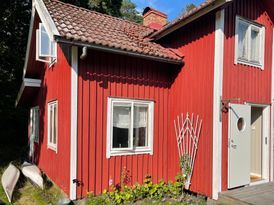 Rött stenhuggartorp nära hav och skog