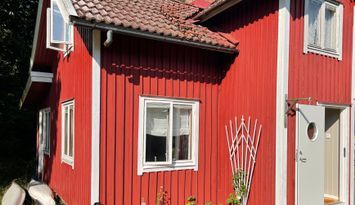 Rött stenhuggartorp nära hav och skog