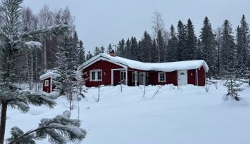 Ombonad stuga vid spår och sjö i Harsa