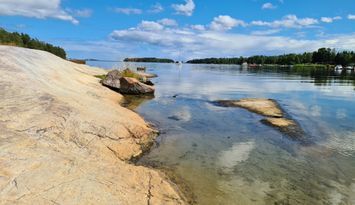 Stuga vid havet, nära strand och skog.