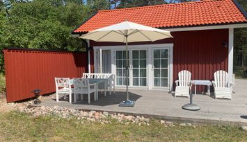 Havsnära nybyggd stuga med roddbåt.