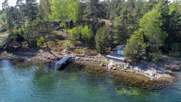 Vacker sjötomt med flera stugor och vedeldad bastu