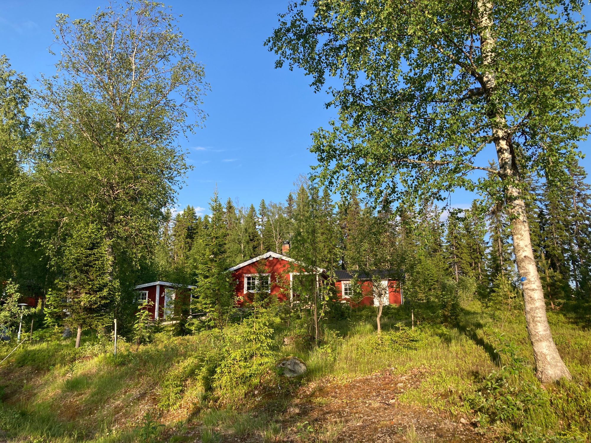 Ombonad stuga vid spår och sjö i Harsa