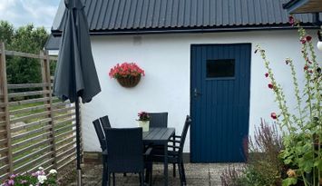 Litet hus vid fruktodling och hage.